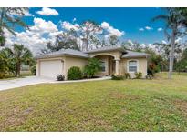 Tan house with a two-car garage and lush lawn at 4522 Mckay St, North Port, FL 34286