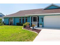 Front view of a charming teal home with well-maintained landscaping at 18147 Cadillac Ave, Port Charlotte, FL 33948