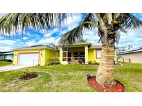 Bright yellow house with red trim, palm trees, and a well-manicured lawn at 18204 Ackerman Ave, Port Charlotte, FL 33948