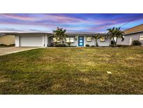 Charming single story home with a white exterior, blue door, and well-manicured lawn at 226 Spring Lake Nw Blvd, Port Charlotte, FL 33952