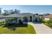 One-story house with a green facade, palm trees, and a curved driveway at 23511 Lark Ave, Port Charlotte, FL 33954