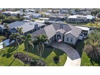 Aerial view of a single-Gathering home with a circular driveway, lush landscaping, and canal access at 2824 Caribbean Dr, Punta Gorda, FL 33950