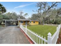 Cute yellow house with carport, white picket fence, and well-manicured lawn at 103 Atwater St, Port Charlotte, FL 33954