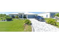 Single-story home with gray paver driveway and landscaped lawn at 14303 Maysville Cir, Port Charlotte, FL 33981