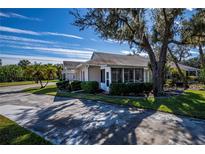 Tan house with a screened porch and two-car garage, surrounded by lush landscaping at 1447 Red Oak Ln, Port Charlotte, FL 33948