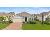 Single-story home with a brick driveway, landscaping, and two-car garage at 3861 Cobblestone Ln, Port Charlotte, FL 33980