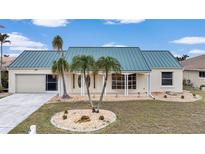 Single-story home with a green metal roof and landscaped yard at 500 Belvedere Ct, Punta Gorda, FL 33950