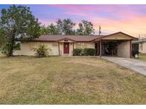 Ranch-style home with carport, spacious lawn, and red door at 168 Dartmouth Nw Dr, Port Charlotte, FL 33952