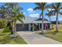 Single-story home with metal roof, gray exterior, and palm trees at 17654 Vellum Cir, Punta Gorda, FL 33955