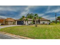 Single-story home with landscaped lawn, palm trees, and a two-car garage at 245 Brighton Ct, Englewood, FL 34223