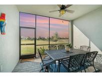 A covered outdoor dining area features decorative table and chairs with views of a sunset over the pond at 43996 Boardwalk Loop # 1411, Punta Gorda, FL 33982