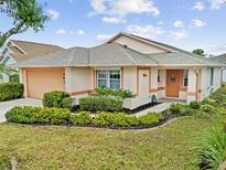 Single-story home with a peach-colored facade, neatly landscaped lawn, and a two-car garage at 483 Winwood Ct, Port Charlotte, FL 33954