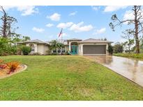 Single-story home with a landscaped lawn, attached garage, and teal front door at 5273 Crestline Ter, Port Charlotte, FL 33981