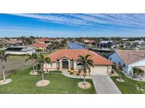 Aerial view of waterfront home with canal access, lush landscaping, and nearby residences at 720 Bimini Ln, Punta Gorda, FL 33950