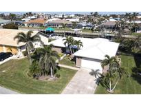 Single-story home with a white roof, palm trees, and a paved driveway, located in a waterfront community at 1022 Lucia Dr, Punta Gorda, FL 33950