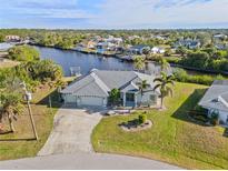 Aerial view of waterfront home with canal access, lush landscaping, and a two-car garage at 17456 Foremost Ln, Port Charlotte, FL 33948