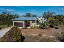 Single-story house with metal roof, attached garage, and landscaped yard at 24362 Yacht Club Blvd, Punta Gorda, FL 33955
