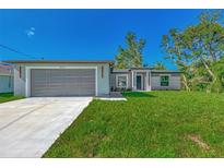 Newly constructed home with a gray exterior, attached garage, and well-manicured lawn at 5049 Birdsong St, North Port, FL 34291