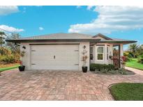 White house with gray roof, white garage door, and brick paver driveway at 102 Linda Lee Dr, Rotonda West, FL 33947