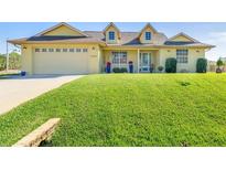 Attractive yellow house with a two-car garage and well-maintained lawn at 1020 Caliva St, North Port, FL 34286