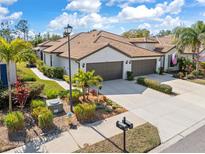 Beautifully landscaped house with a beige exterior, brown roof, and spacious three-car garage at 2860 Arugula Dr, North Port, FL 34289