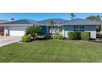 Single-story home with a metal roof, landscaping, and a paved driveway at 2871 Coral Way, Punta Gorda, FL 33950