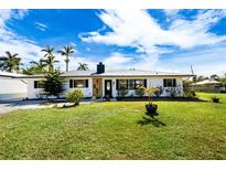 Newly renovated home with a modern exterior, featuring a metal roof and landscaped lawn at 3429 Sleepy Hollow Ln, Punta Gorda, FL 33950