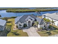 Single-story home with a dark gray metal roof, waterfront location, and lush landscaping at 5189 Collingswood Blvd, Port Charlotte, FL 33948