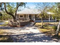 Gray house with wood deck and stone pathway, surrounded by lush trees at 5301 Sabal Palm Ln, Punta Gorda, FL 33982