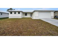 Single-story house with white exterior, attached garage, and grassy front yard at 85 Snedeker St, Port Charlotte, FL 33954