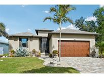 Attractive single-story home with a wood garage door and landscaped yard at 316 Antis Dr, Rotonda West, FL 33947