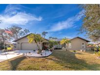 Tan single-story house with palm trees, nicely landscaped lawn, and a paved driveway at 157 Angol St, Punta Gorda, FL 33983