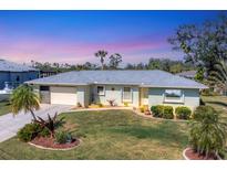 Charming single-story home with lush lawn, manicured landscaping and a two-car garage at 18390 Burkholder Cir, Port Charlotte, FL 33948