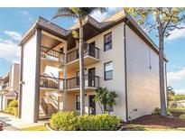 Condo building with multiple floors, featuring balconies, landscaping, and a mature palm tree at 1999 Kings Hwy # 16B, Punta Gorda, FL 33980