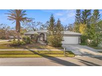 Single-story home with a gray exterior, white garage door, and well-manicured landscaping at 2202 Gold Oak Ln, Sarasota, FL 34232