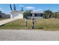 Charming single-story home featuring a well-manicured lawn and attached garage with a classic mailbox in the front yard at 2461 Ivanhoe St, Port Charlotte, FL 33952