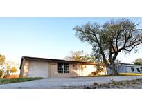 Tan single-story house with a white garage door and large tree in front at 4200 Kilpatrick St, Port Charlotte, FL 33948