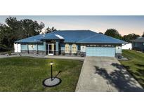 Single-story home with metal roof, light blue siding, and landscaped lawn at 7435 Snow Dr, Englewood, FL 34224