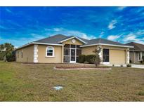 Tan house with gray roof, screened porch, and two-car garage at 110 Albatross Rd, Rotonda West, FL 33947