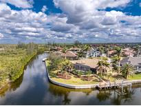 An aerial view of a beautiful waterfront home with a screened-in pool and a private dock on a sunny day at 3507 Marsala Ct, Punta Gorda, FL 33950