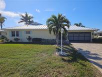 Single-story home with metal roof, landscaped lawn, and paved driveway at 529 Belvedere Ct, Punta Gorda, FL 33950