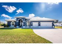 Beautiful home featuring a metal roof, attached three-car garage, manicured lawn and tasteful landscaping at 1052 Eppinger Dr, Port Charlotte, FL 33953