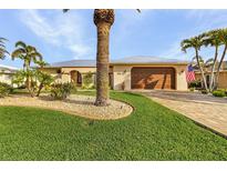 Tan house with metal roof, palm trees, landscaped yard, and paved driveway at 2198 El Cerito Ct, Punta Gorda, FL 33950