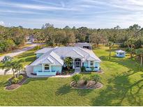 Blue house and landscaping are shown in this property's aerial view at 18181 Bly Ave, Port Charlotte, FL 33948