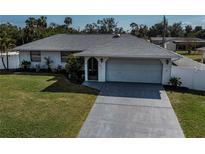 Charming single-story home featuring a two-car garage, well-maintained lawn, and beautiful landscaping at 20431 Calder Ave, Port Charlotte, FL 33954