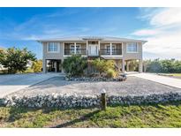 Charming elevated two-story home with lovely landscaping and a light grey exterior at 24343 Pirate Harbor Blvd, Punta Gorda, FL 33955