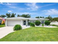 Single-story home with attached garage, landscaping, and a spacious lawn at 4059 Twinbush Ter, North Port, FL 34286