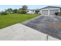 Ranch home with large grassy yard, driveway, and two-car garage at 625 Pompano Ter, Punta Gorda, FL 33950