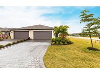 Charming home showcasing a well-manicured lawn, a gray brick driveway and an attached two-car garage at 1912 Saddlewood Cir, Port Charlotte, FL 33953