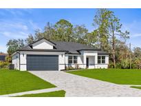 Beautiful, modern single-Gathering home with a well-manicured lawn and a paved driveway leading to a two-car garage at 2143 S Haberland Blvd, North Port, FL 34288